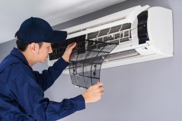 Technician cleaning an AC air filter